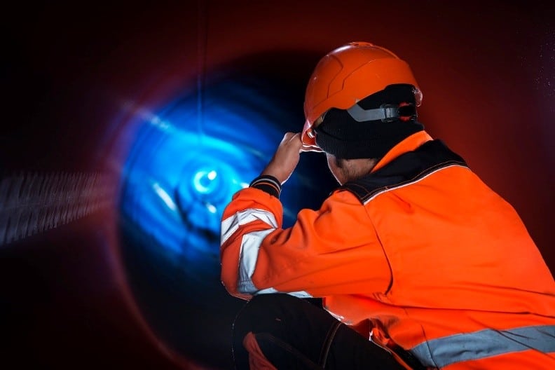 Worker inspecting drainage pipe